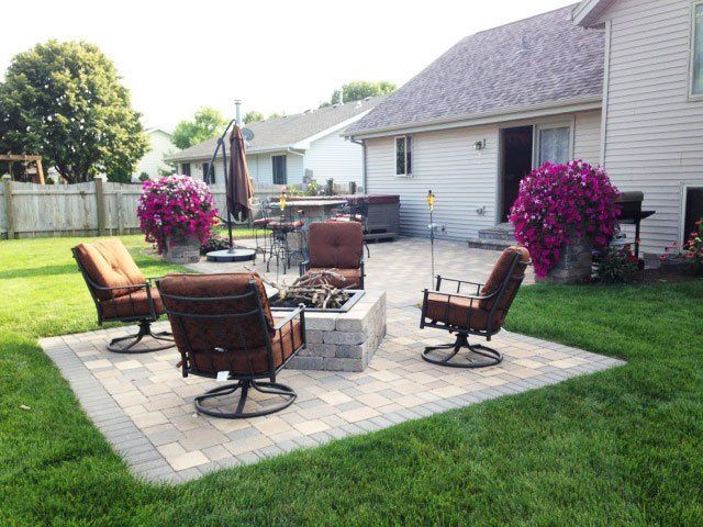 a patio with chairs and a fire pit in front of a house .