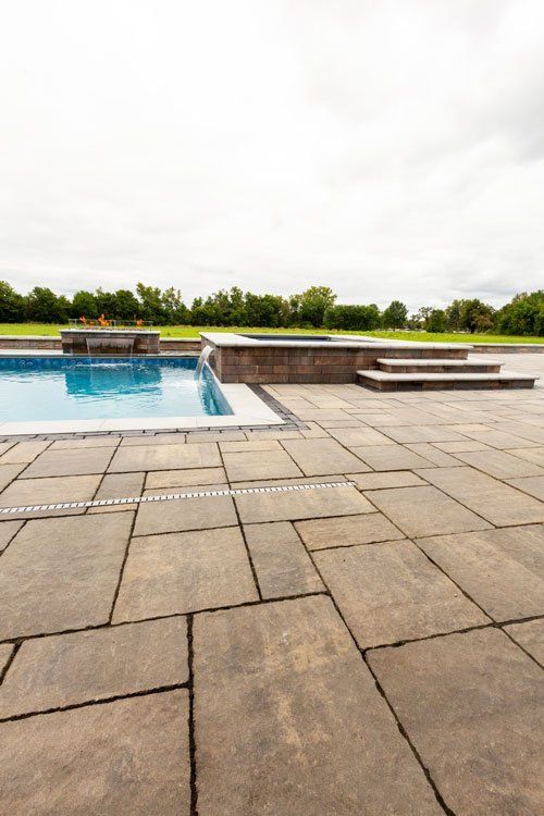 a patio with a swimming pool and a hot tub in the background .