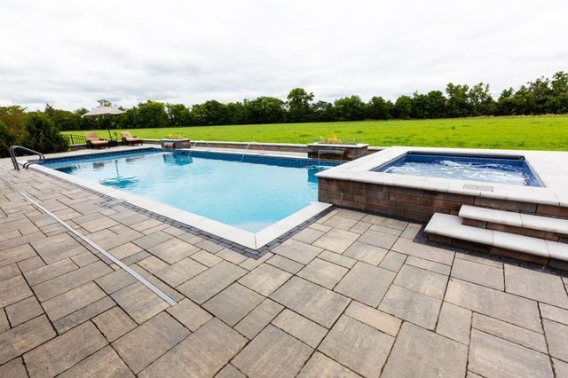 there is a large swimming pool and a hot tub in the backyard .