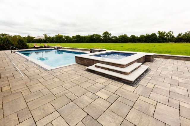 there is a large swimming pool and a hot tub in the backyard .