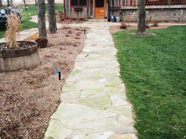 a stone walkway leading to a house with a wooden door .