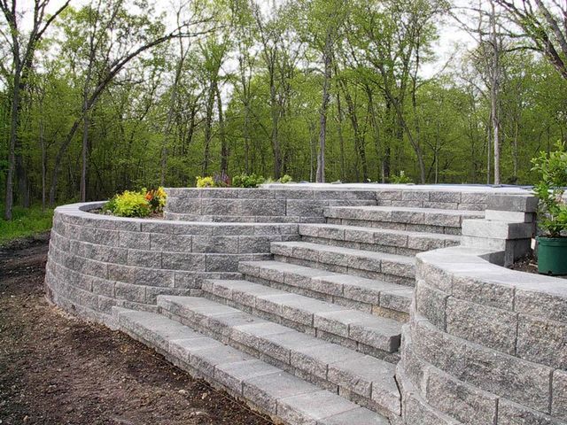 a stone wall with stairs leading up to it in a forest .