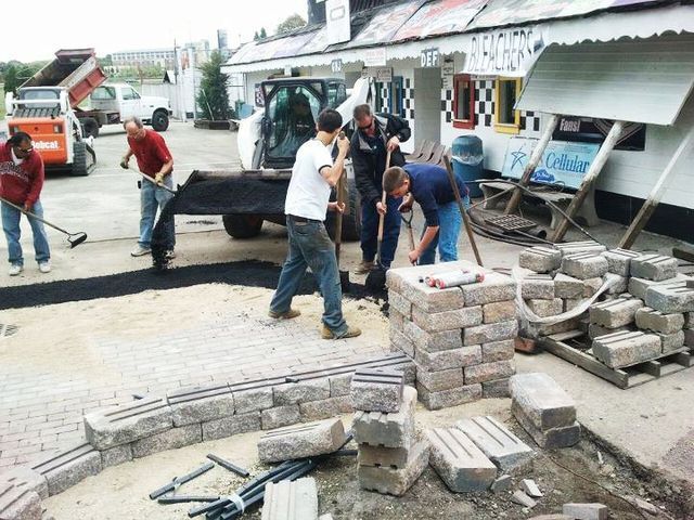 a group of men are working on a construction site in front of a building that has the word motel on it