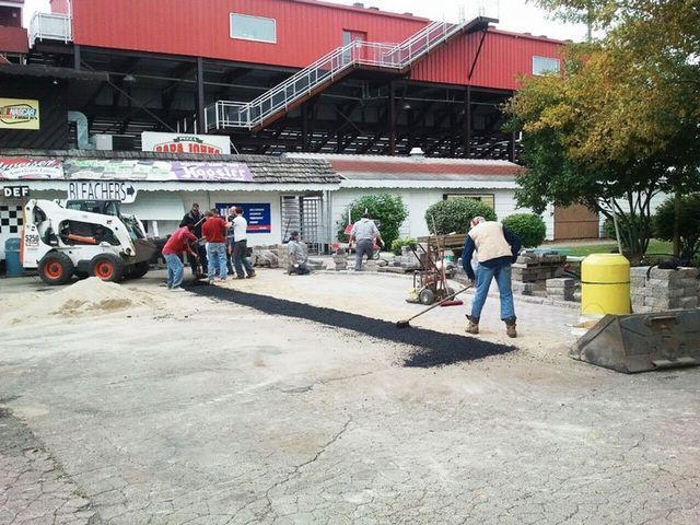 a group of people are working on a road in front of a building that says stp