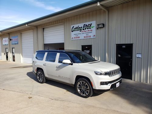 White SUV parked outside a gray auto service shop with open garage doors
