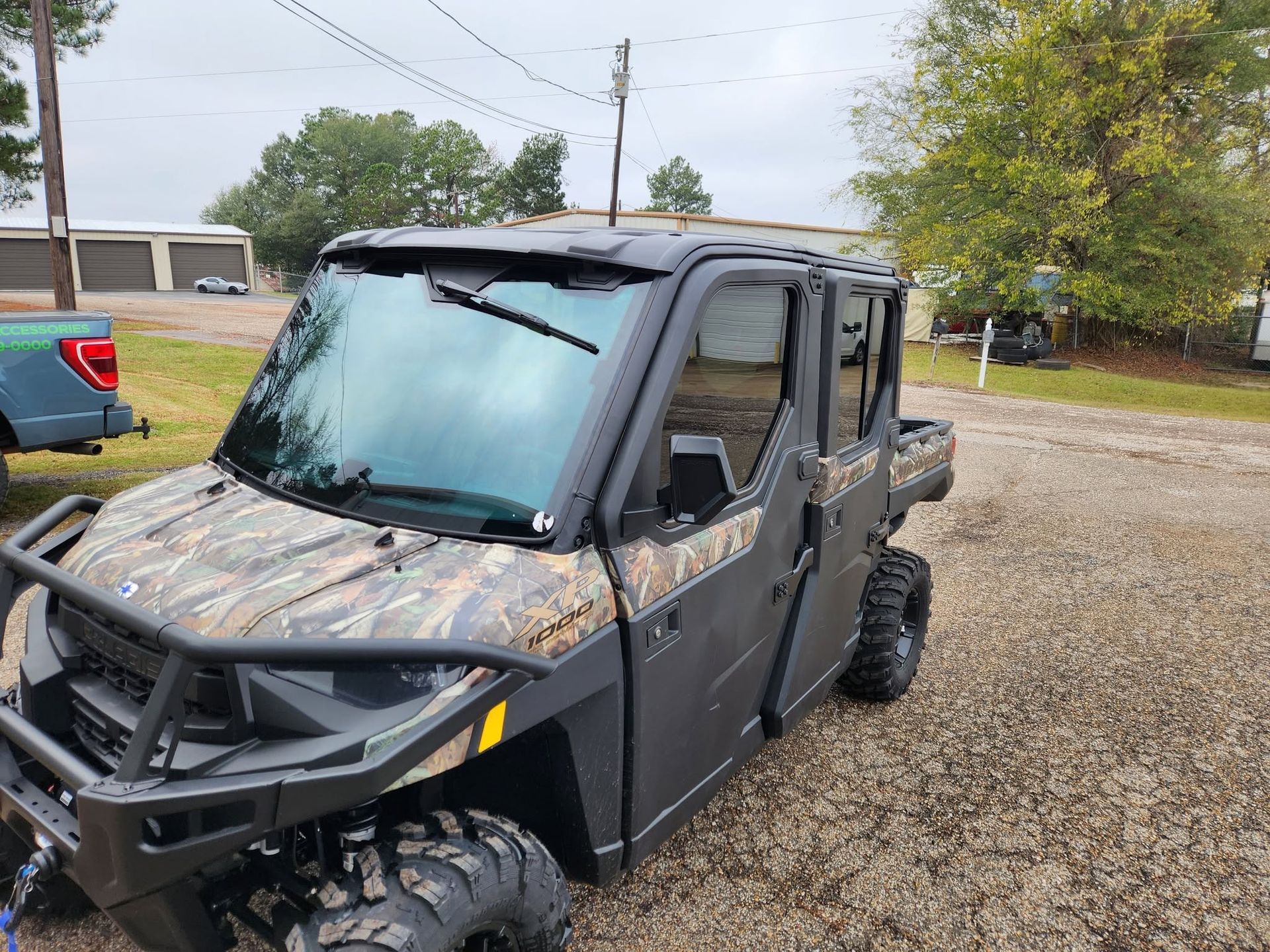 Black off-road utility vehicle on gravel with a camouflage hood and large tires