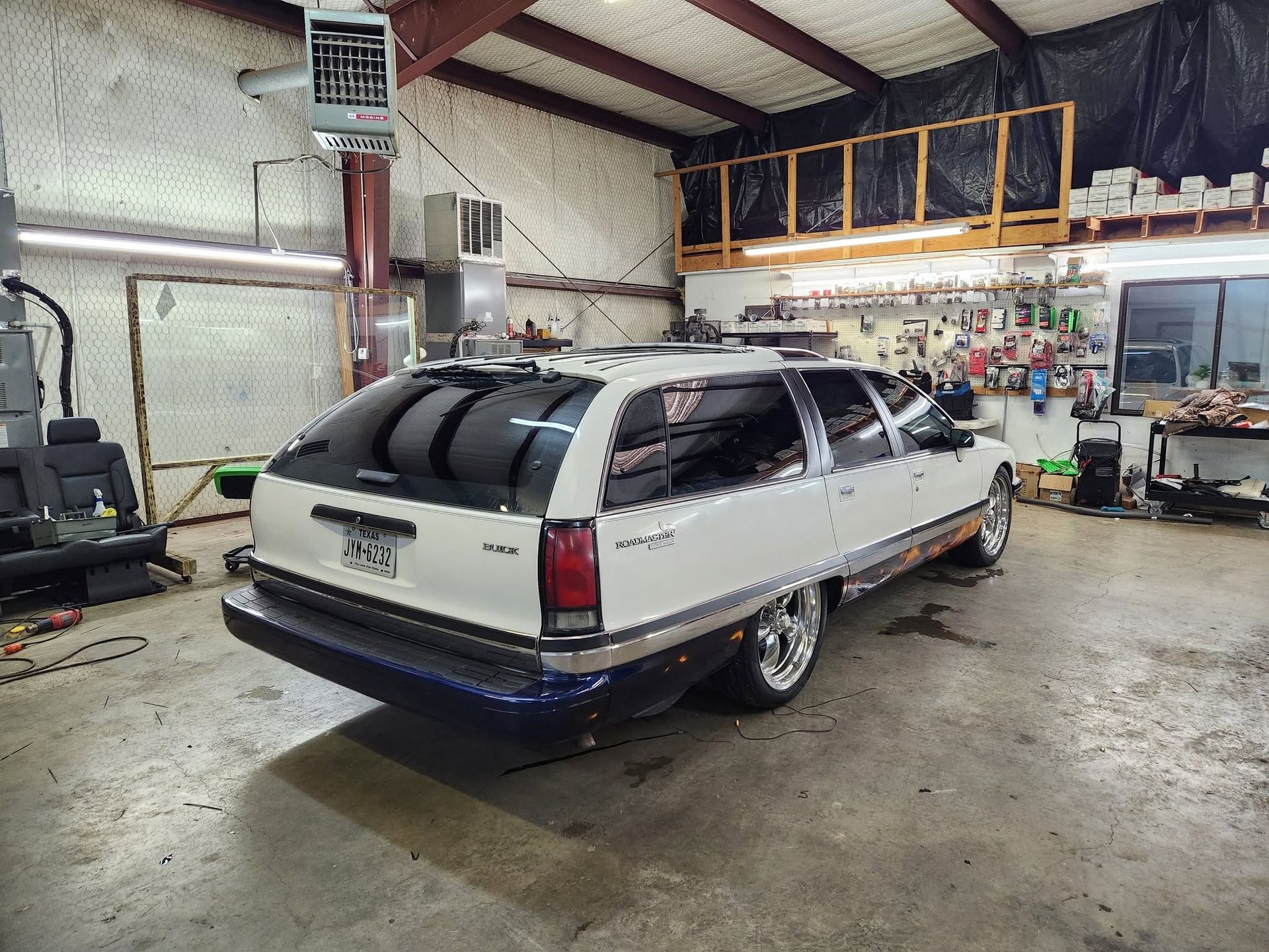 Silver and blue station wagon in a garage workshop, rear view