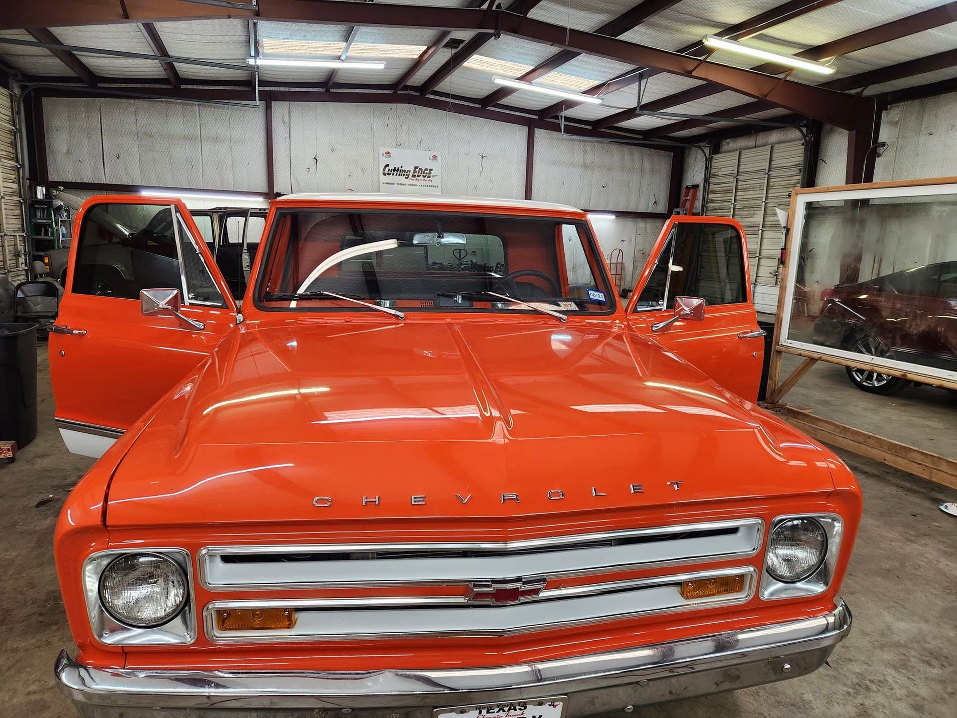 Bright orange vintage pickup truck in a garage with both front doors open