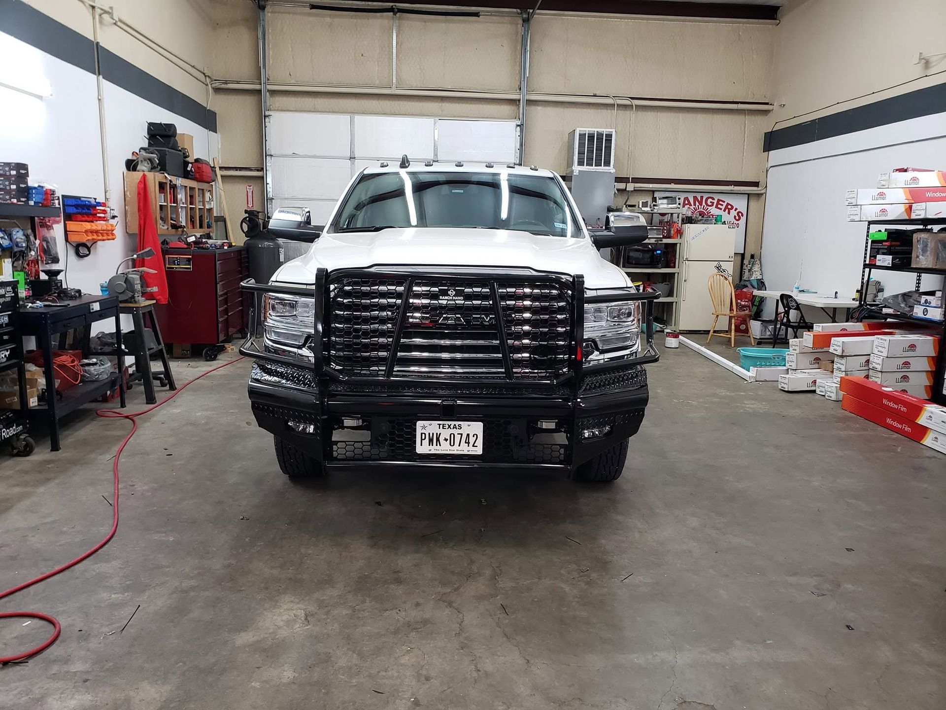 White pickup truck with a black grille guard parked inside a garage workshop