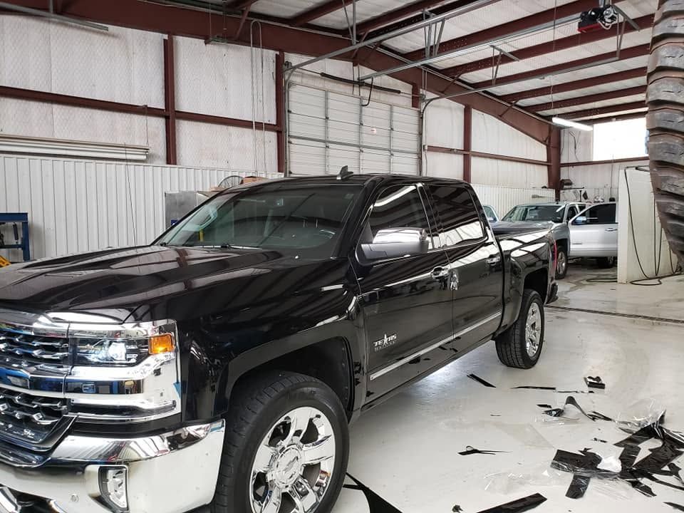 Black pickup truck inside a garage with debris on the floor and a damaged front bumper