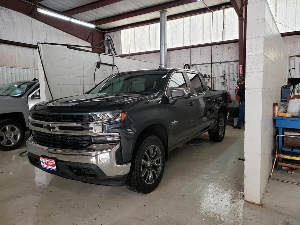 Dark gray pickup truck parked inside a garage with another vehicle beside it