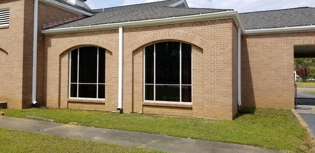 Brick residential facade with two large arched windows and a small front lawn.