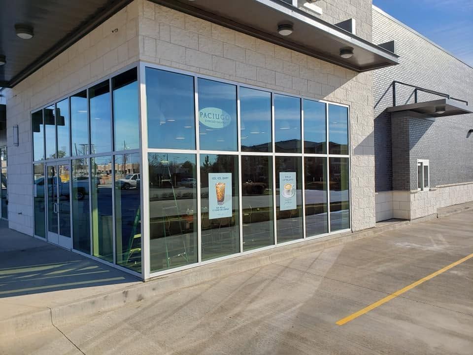 Modern storefront with large glass windows and a concrete walkway on a sunny day