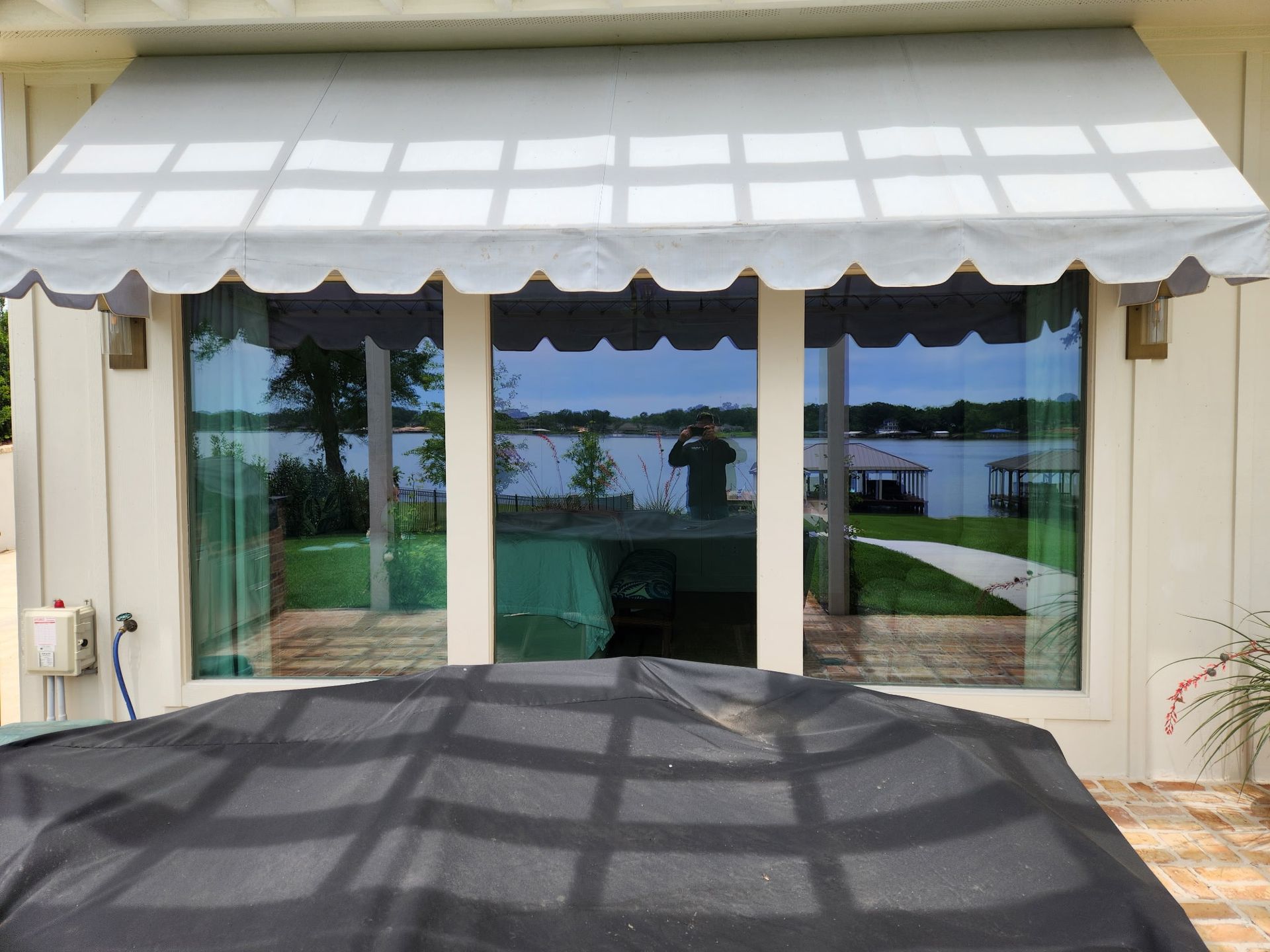 Patio with white awning over glass doors overlooking a pool and lawn