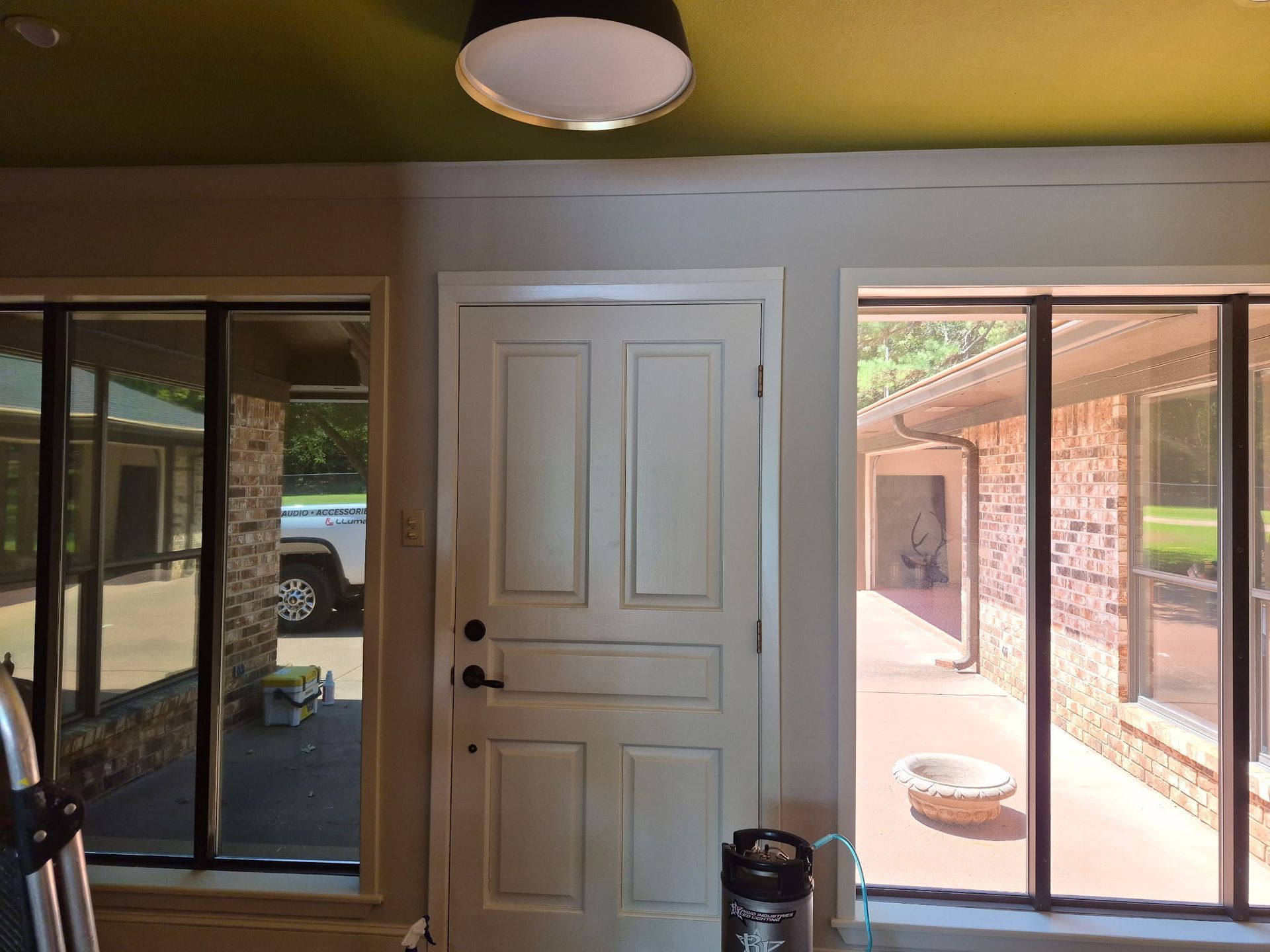 Covered patio with a central white door, sliding glass doors, and a view of the backyard outside.