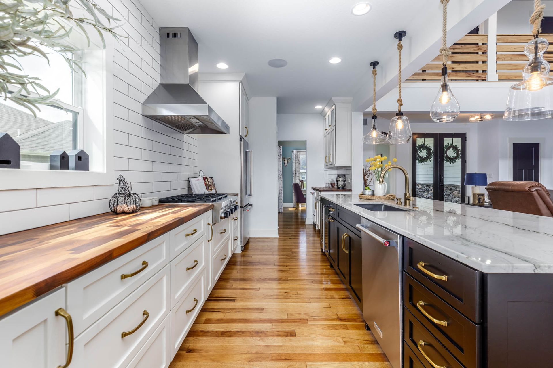 A kitchen with white cabinets, wooden counter tops, and stainless steel appliances