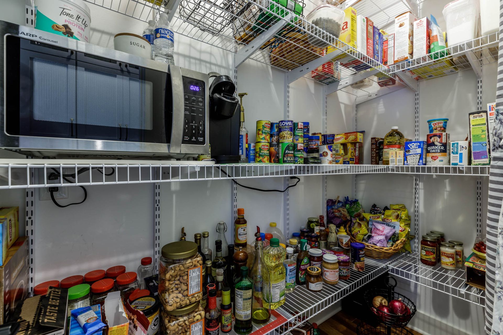 A pantry filled with lots of food and a microwave
