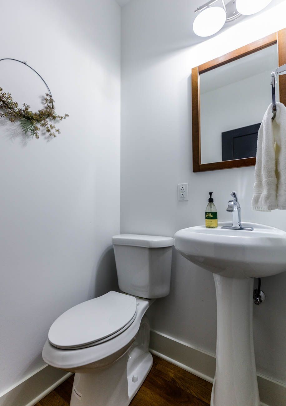 A bathroom with a toilet, sink, and mirror