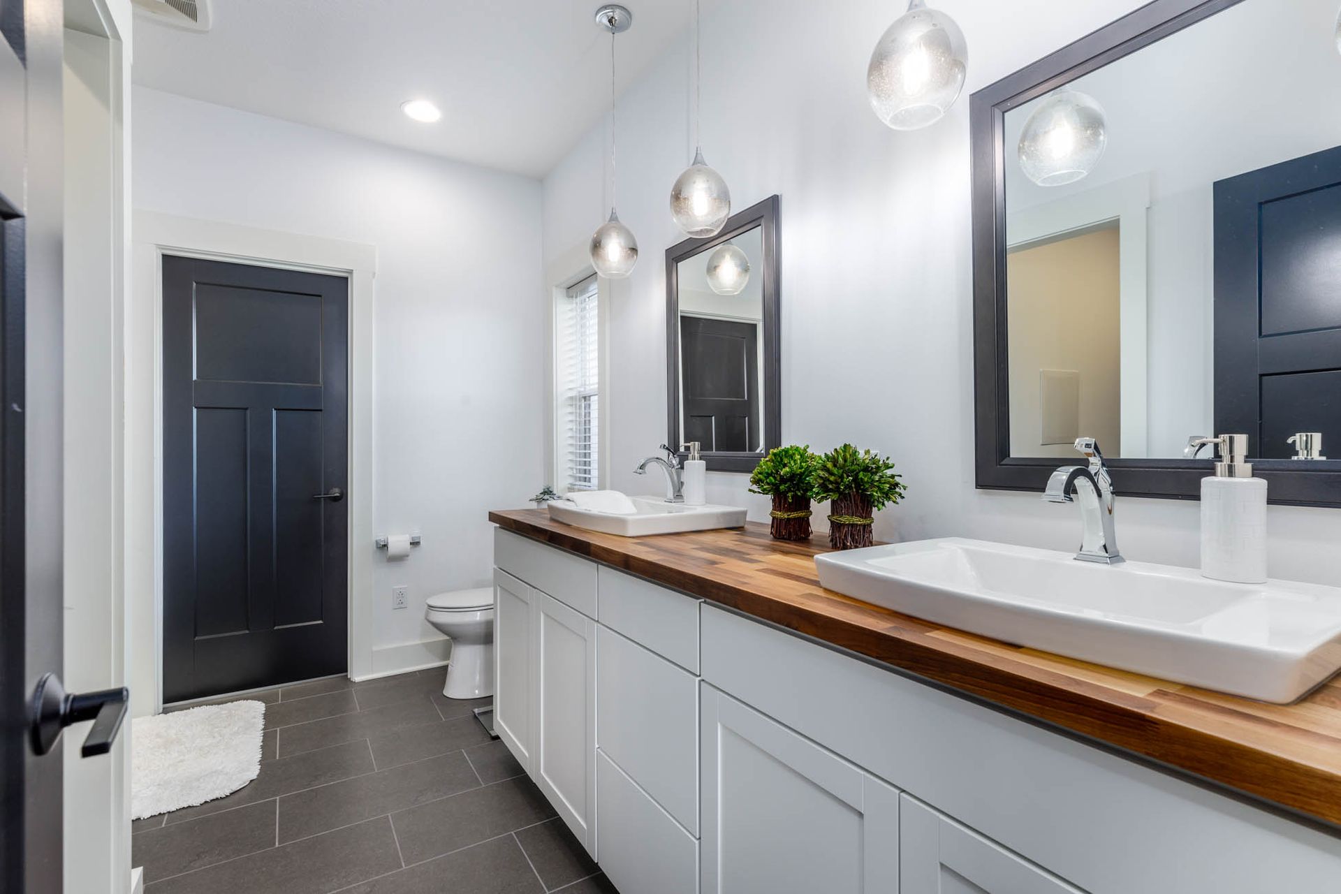 A bathroom with two sinks, two mirrors, and a toilet