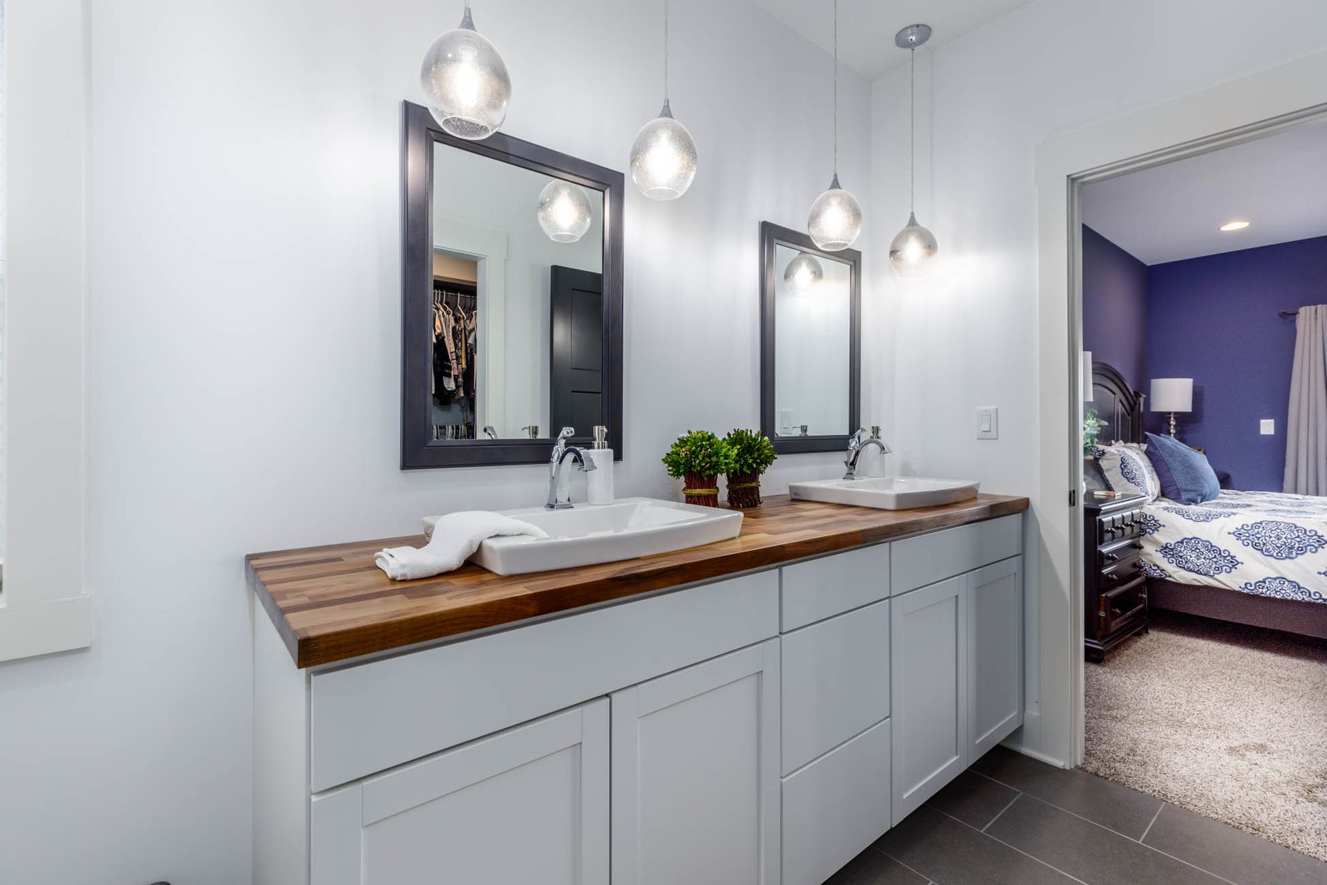 A bathroom with two sinks, two mirrors, and a wooden counter top