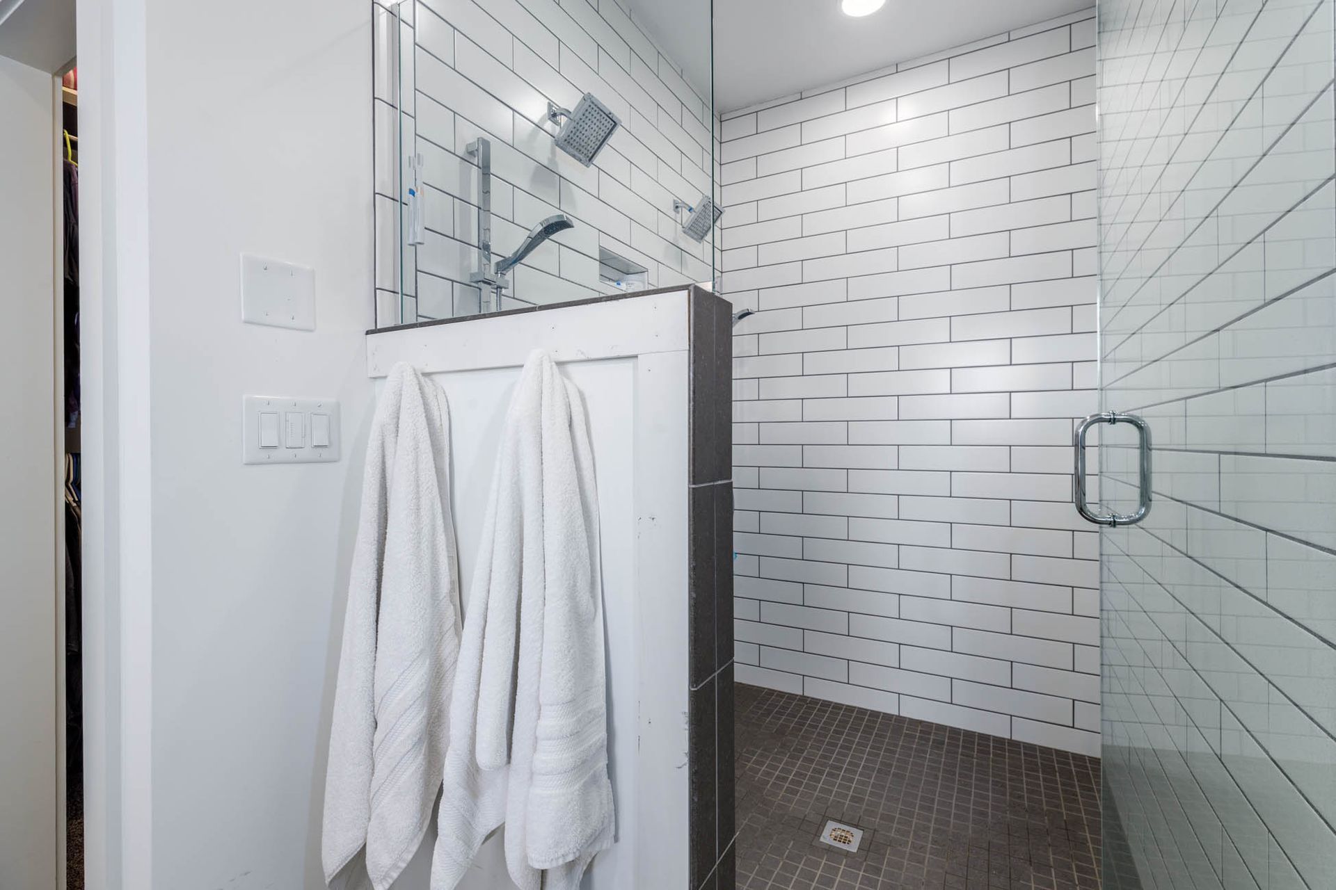 A bathroom with white tiles and a walk in shower