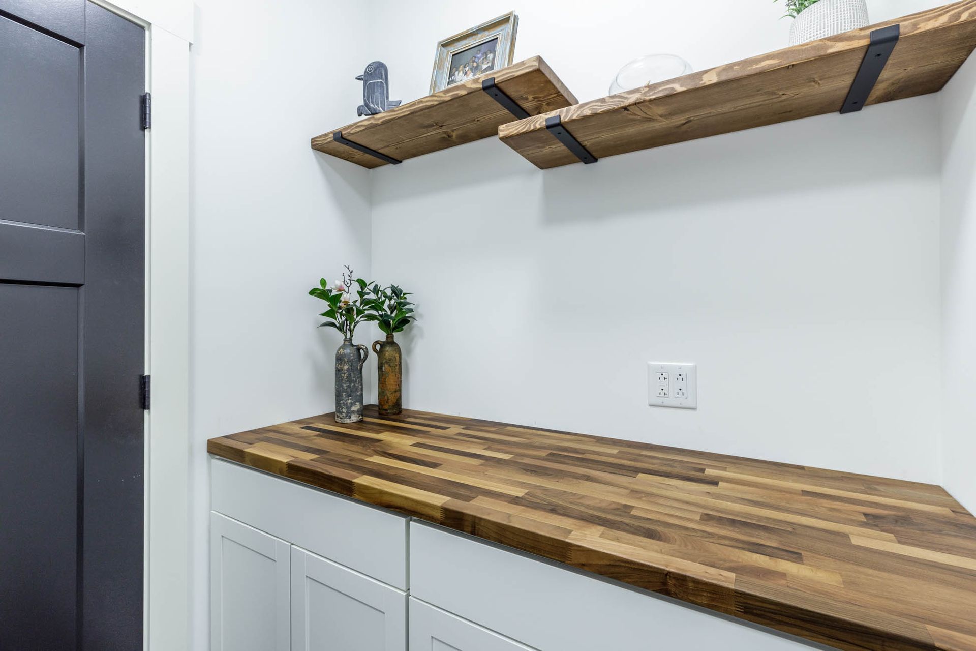A laundry room with a wooden counter top and shelves