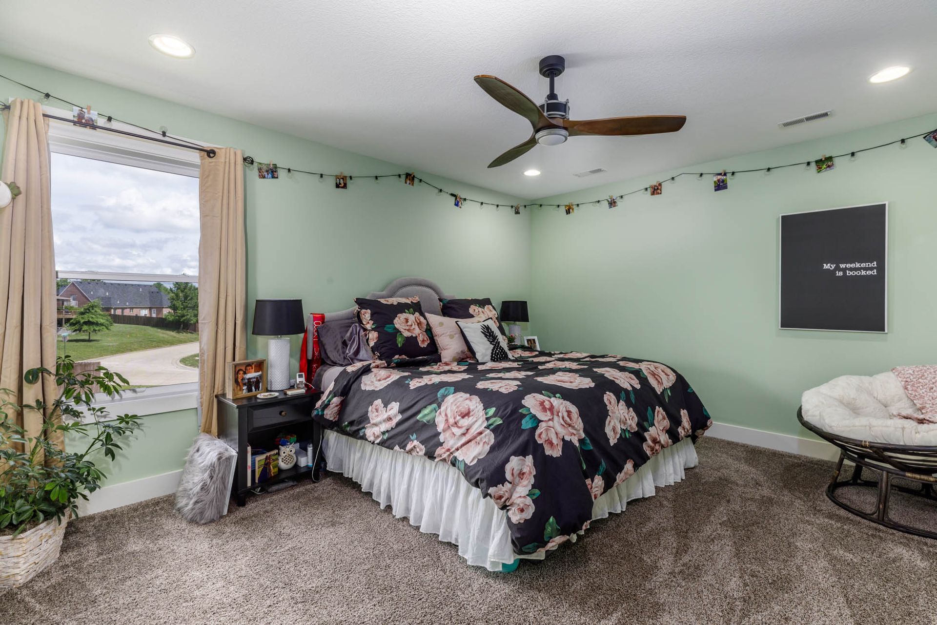 A bedroom with a large bed, a ceiling fan, and a window
