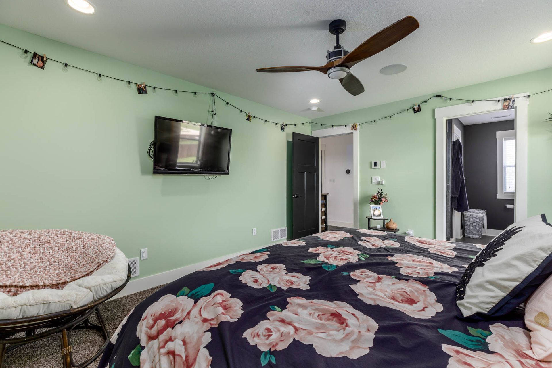 A bedroom with a bed, chair, television, and ceiling fan