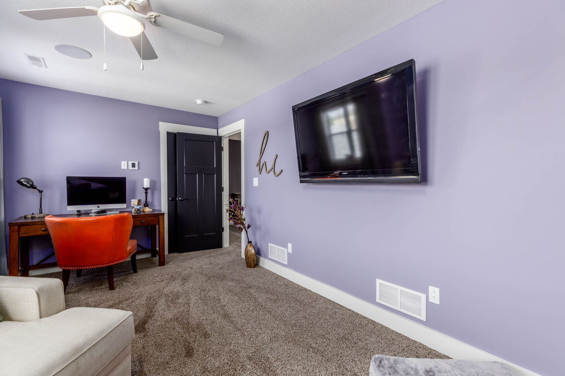 A living room with purple walls and a flat screen tv on the wall