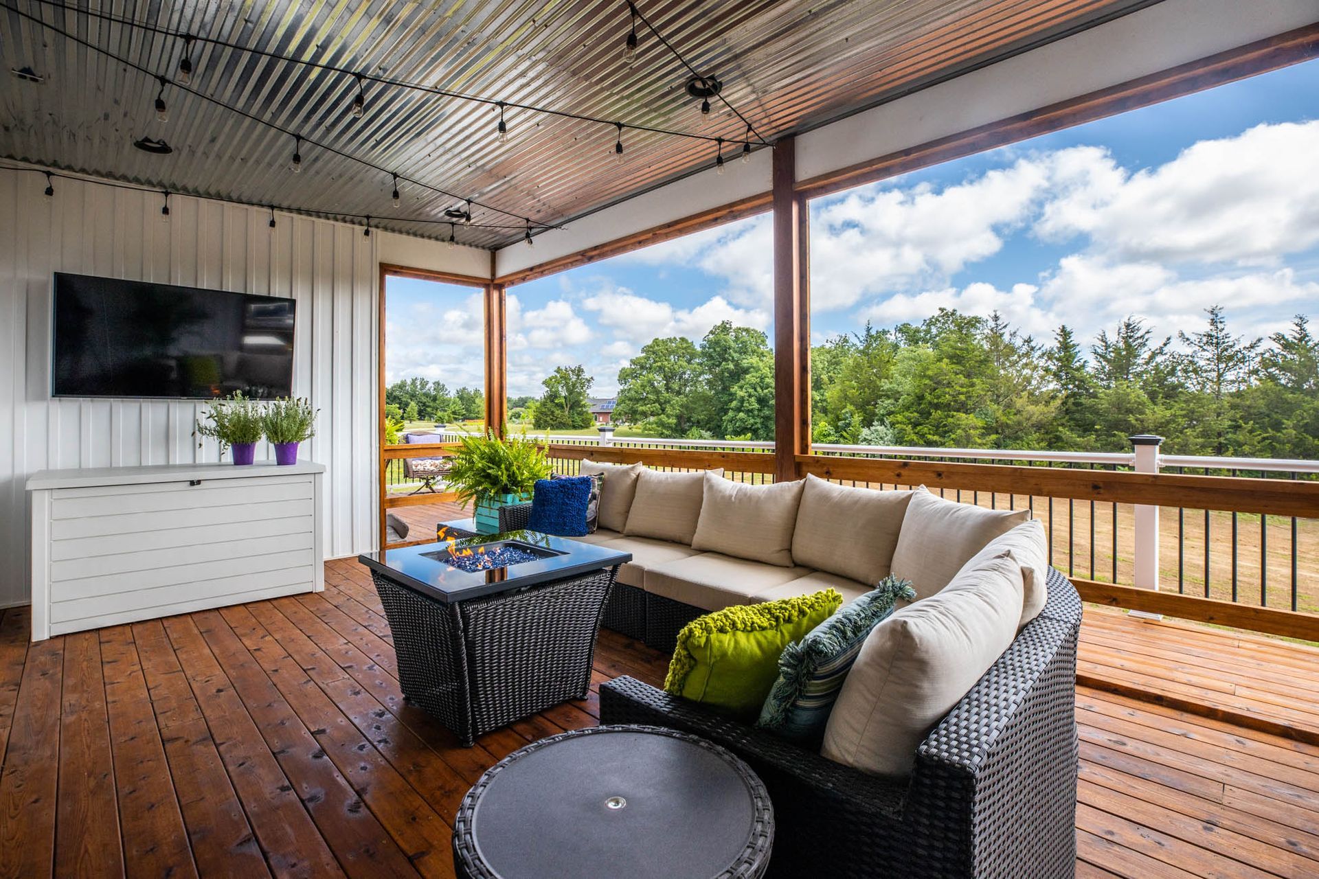A porch with a couch, table, and television
