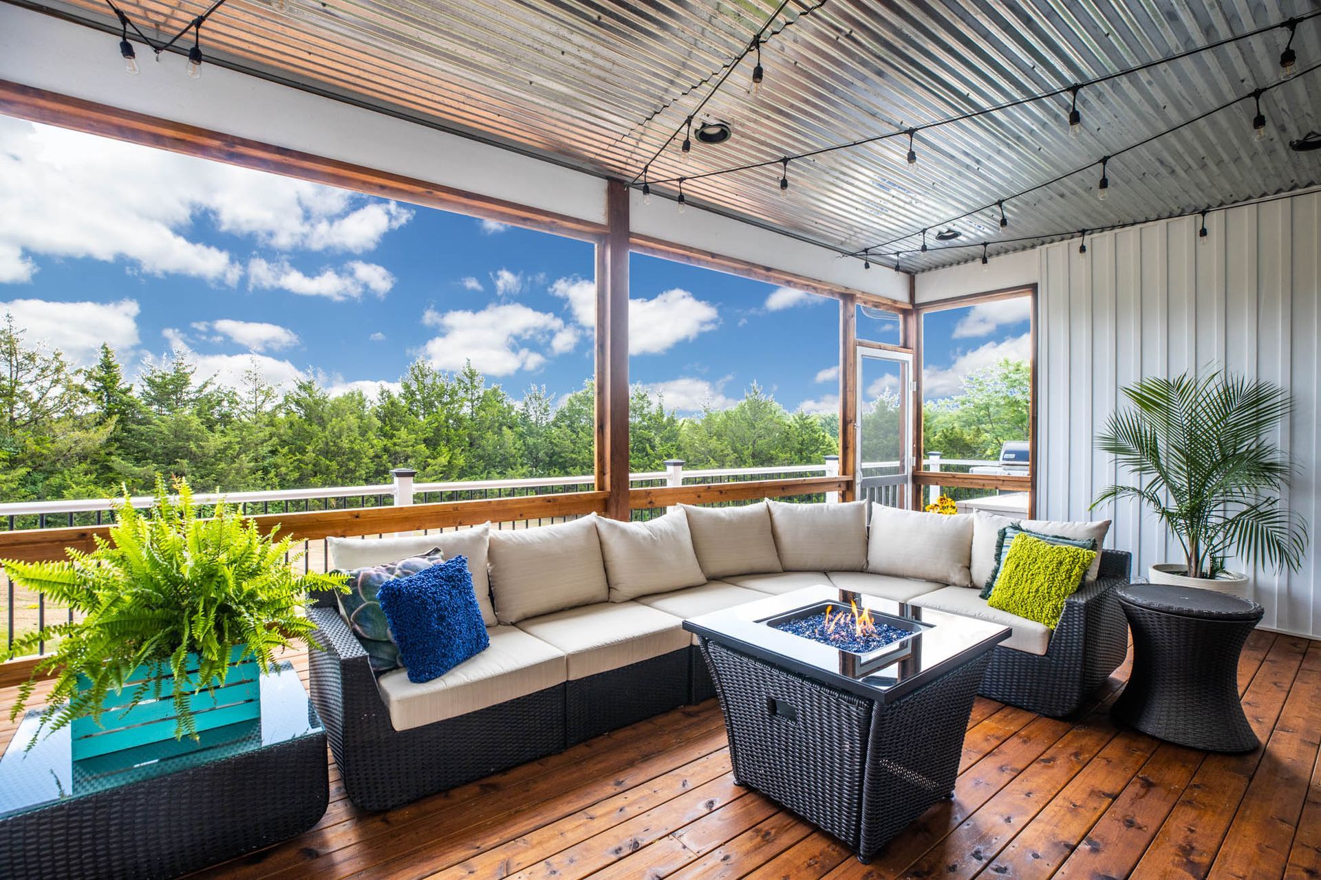 A screened in porch with a couch, chairs, and a fire pit