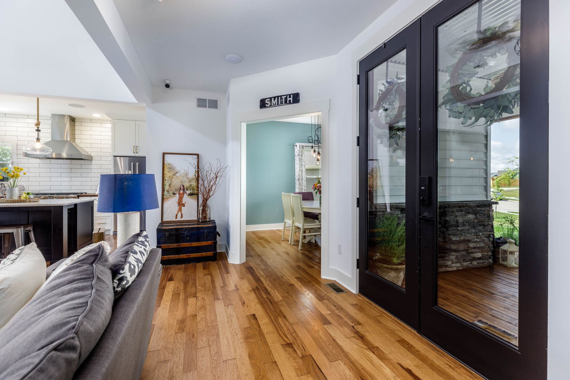 A living room with hardwood floors , a couch and a lamp