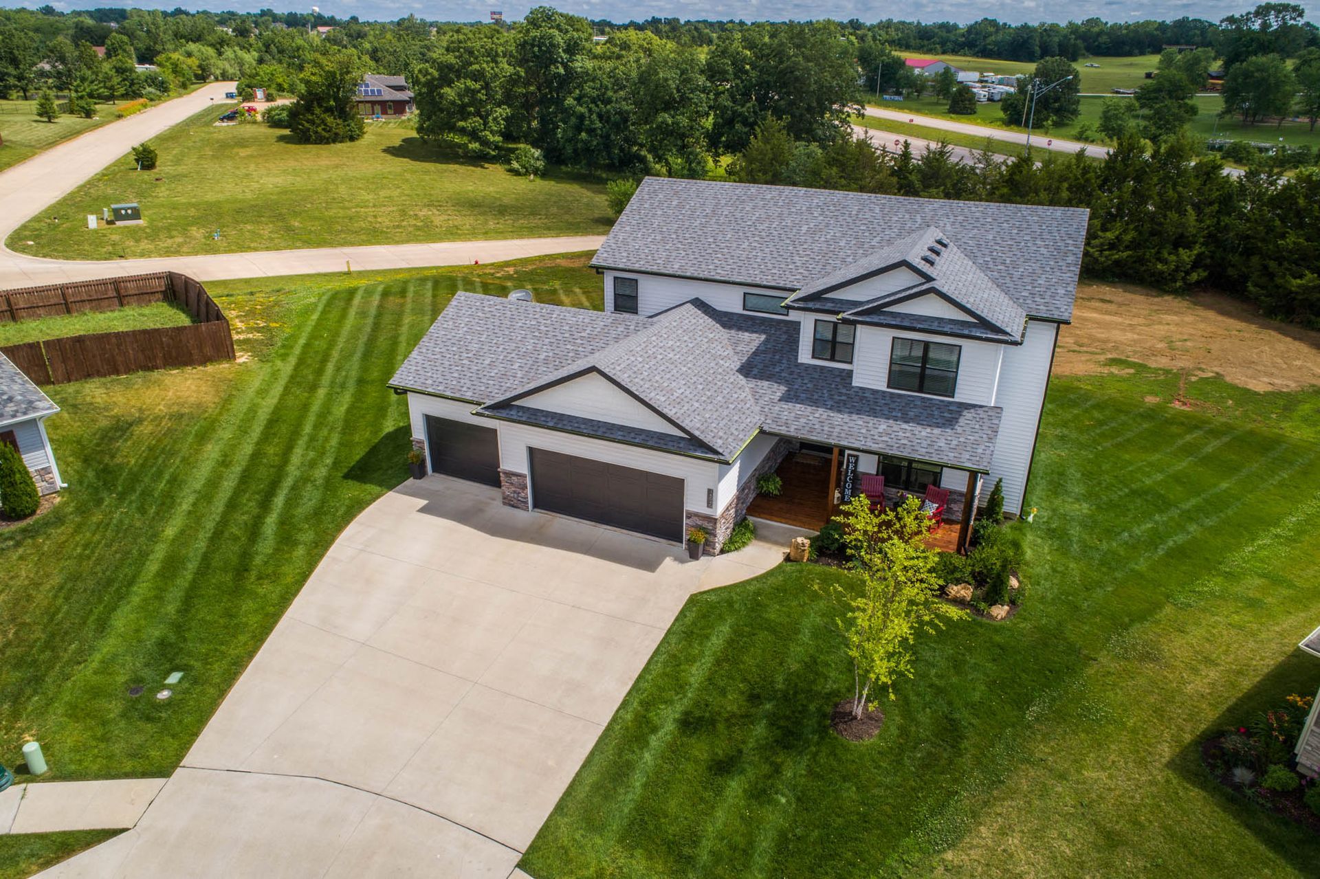 An aerial view of a large white house with a gray roof in a residential area