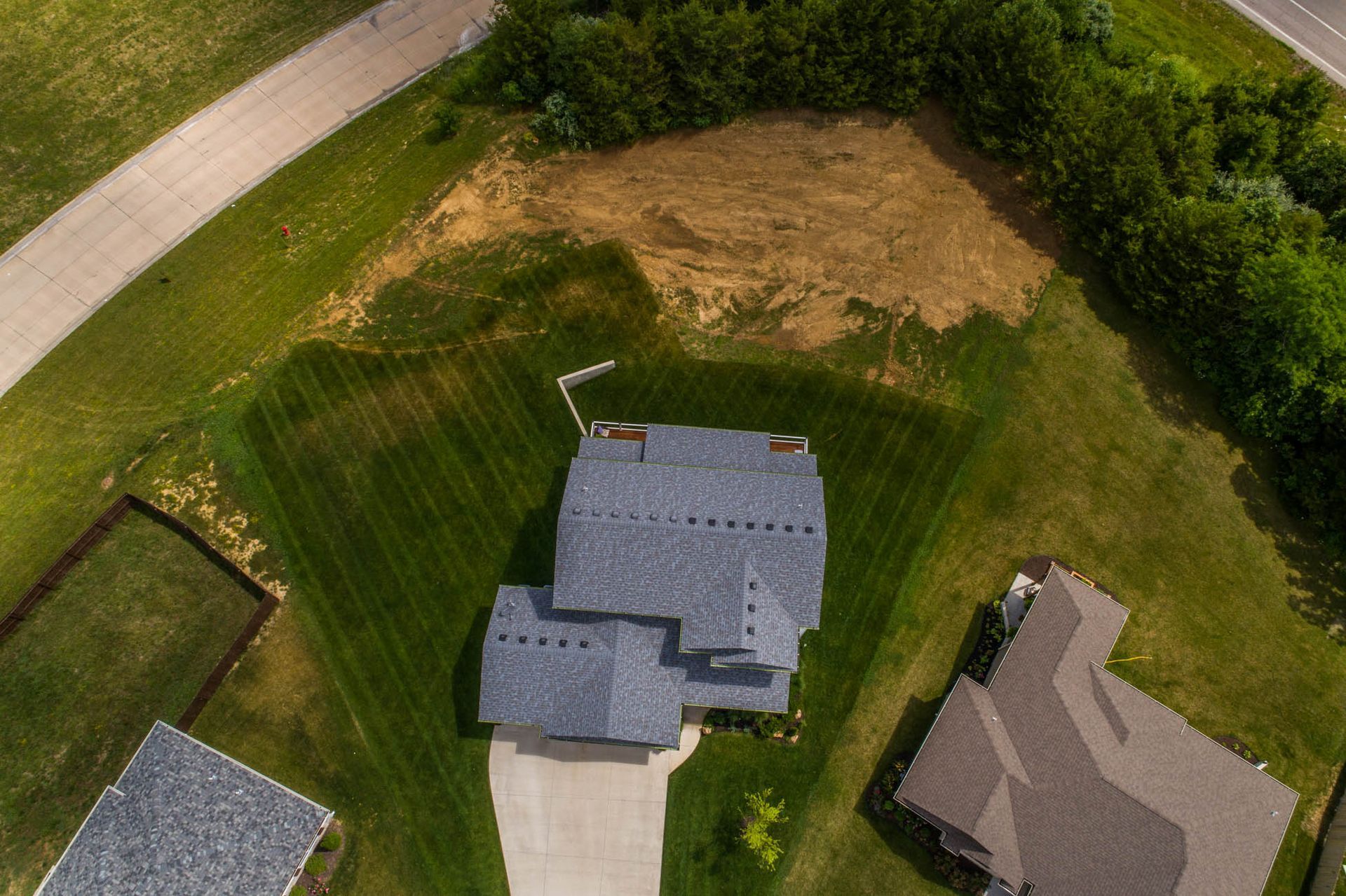 An aerial view of a house with a blue roof and a driveway