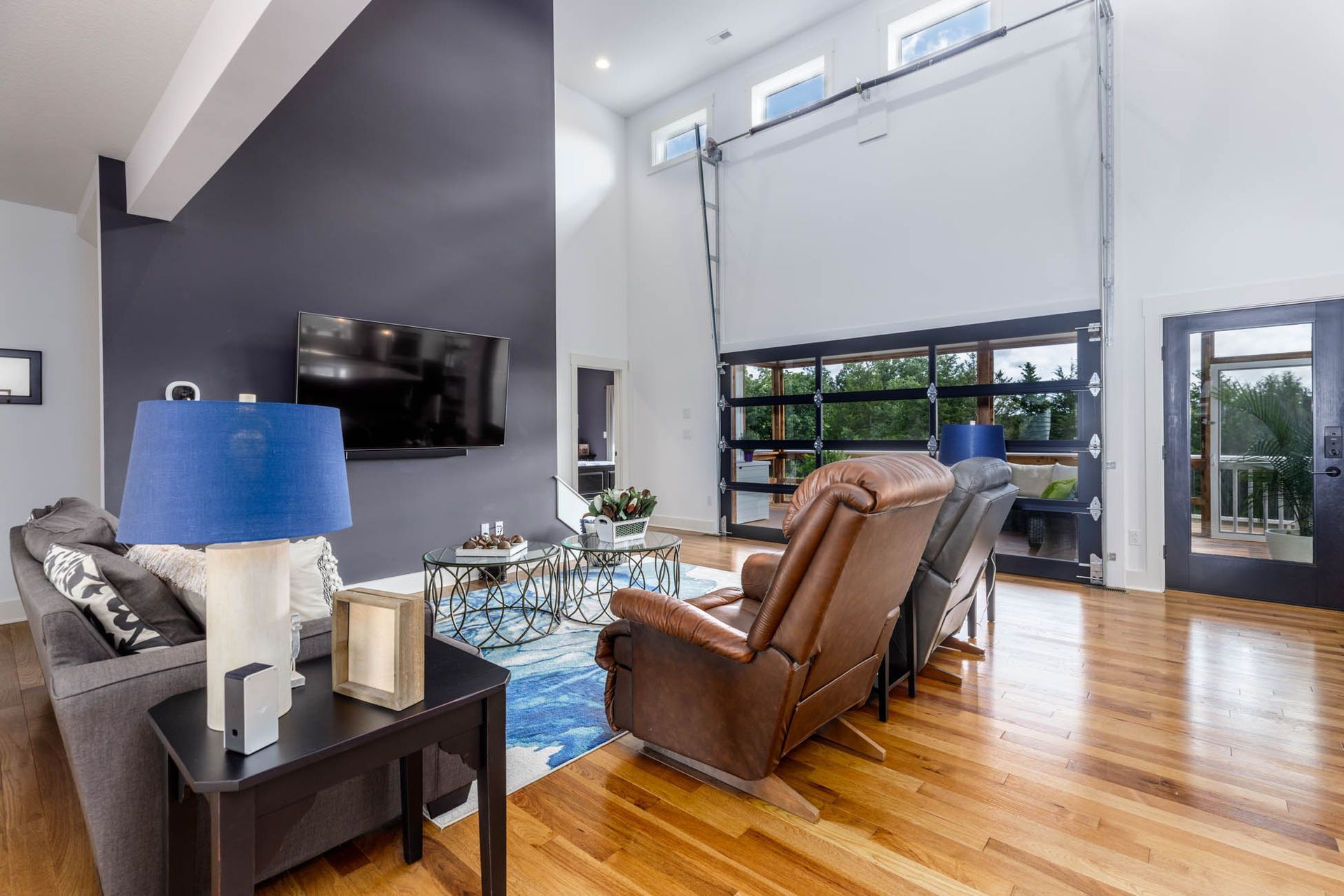 A living room with a couch, chairs, lamps, and a television
