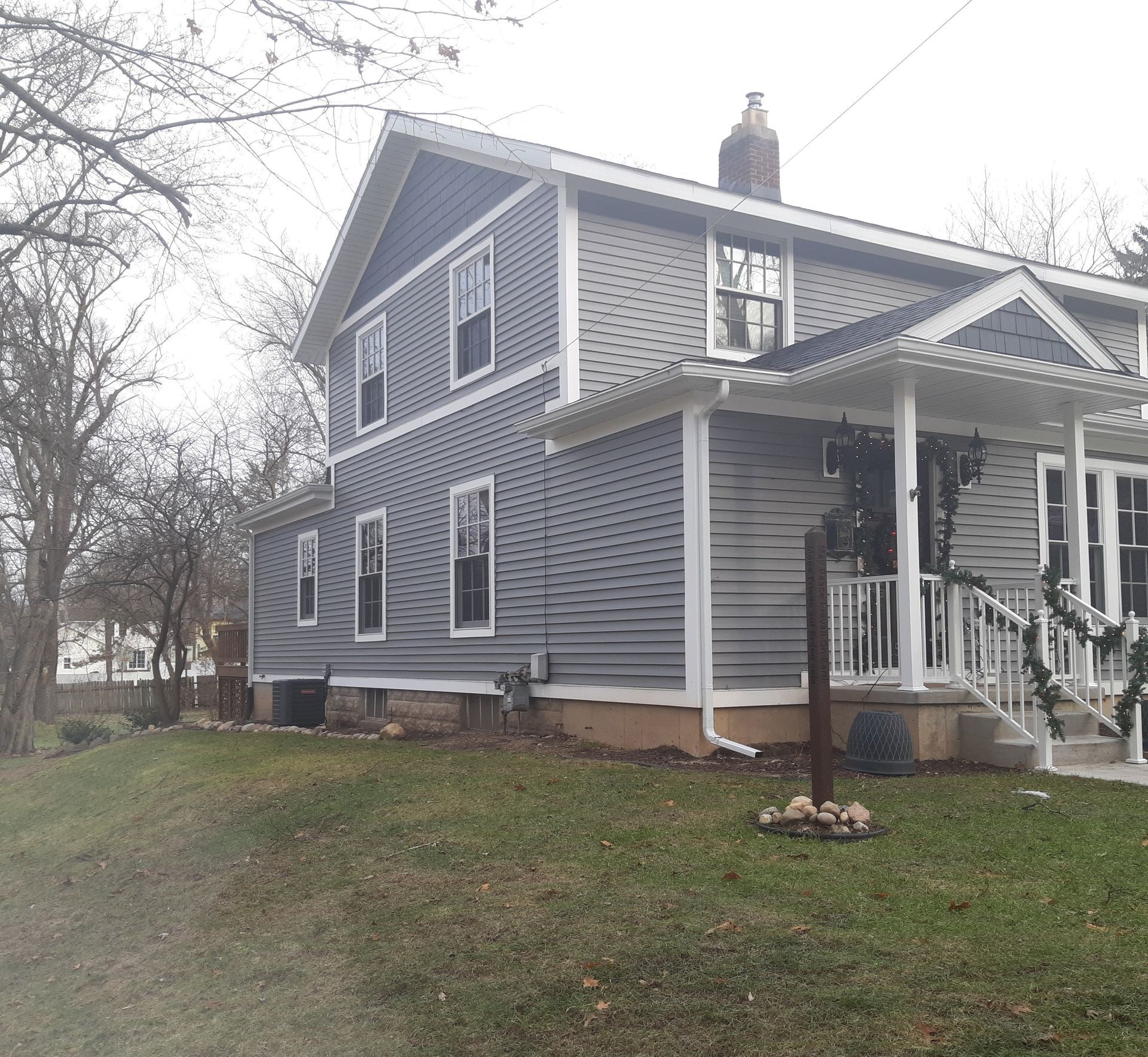 Blue two-story house with white trim and a small front porch on a grassy lot.