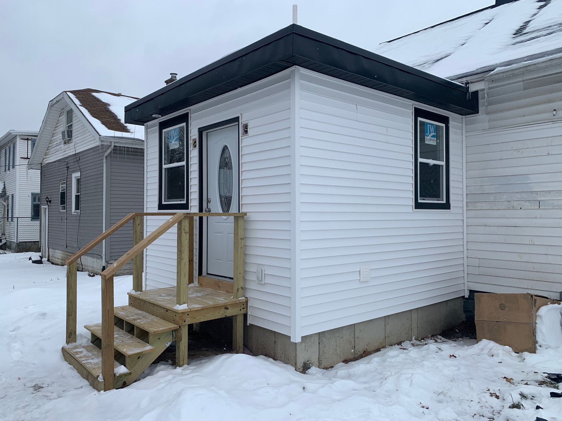 Small white house with front steps and porch in snowy winter setting