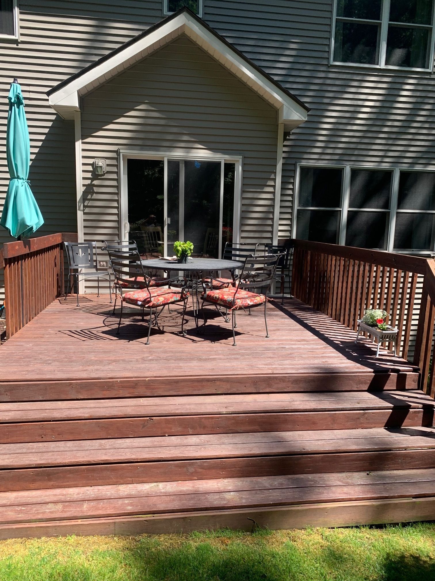 Wooden backyard deck with patio table and chairs in front of a sliding glass door