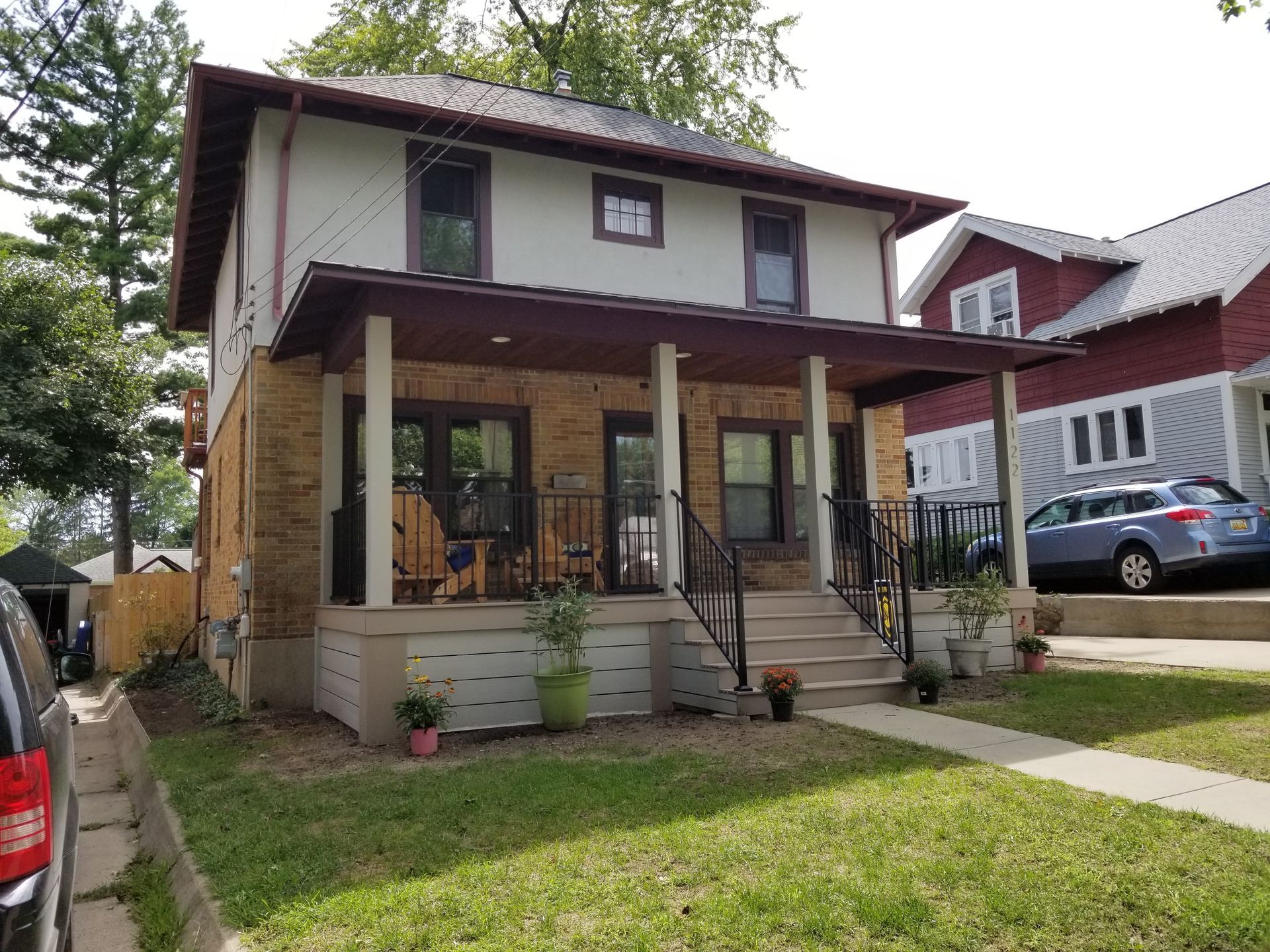 Two-story house with front porch, steps, and lawn in a residential neighborhood