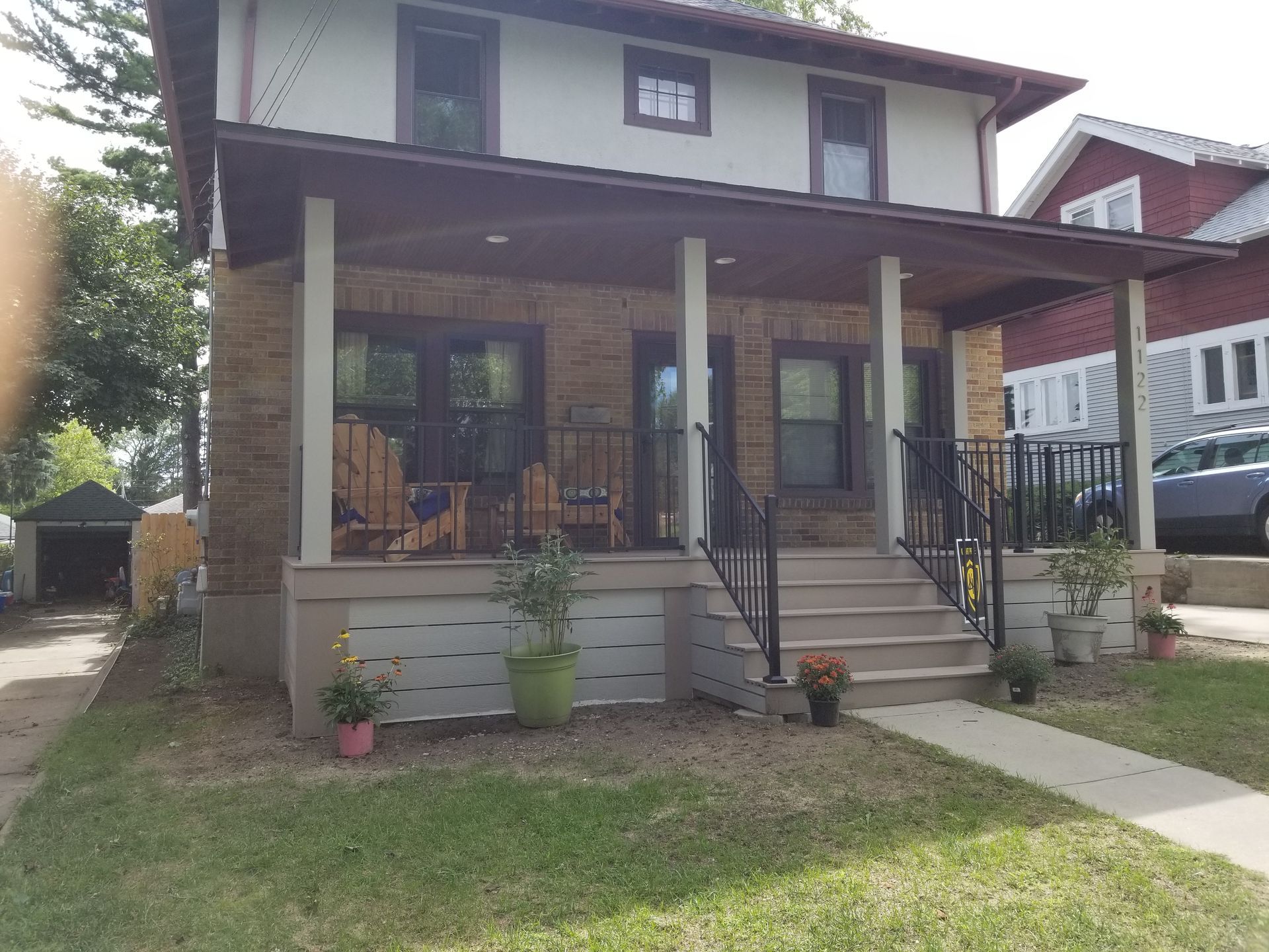 Front view of a two-story house with a covered porch, front steps, and small lawn.