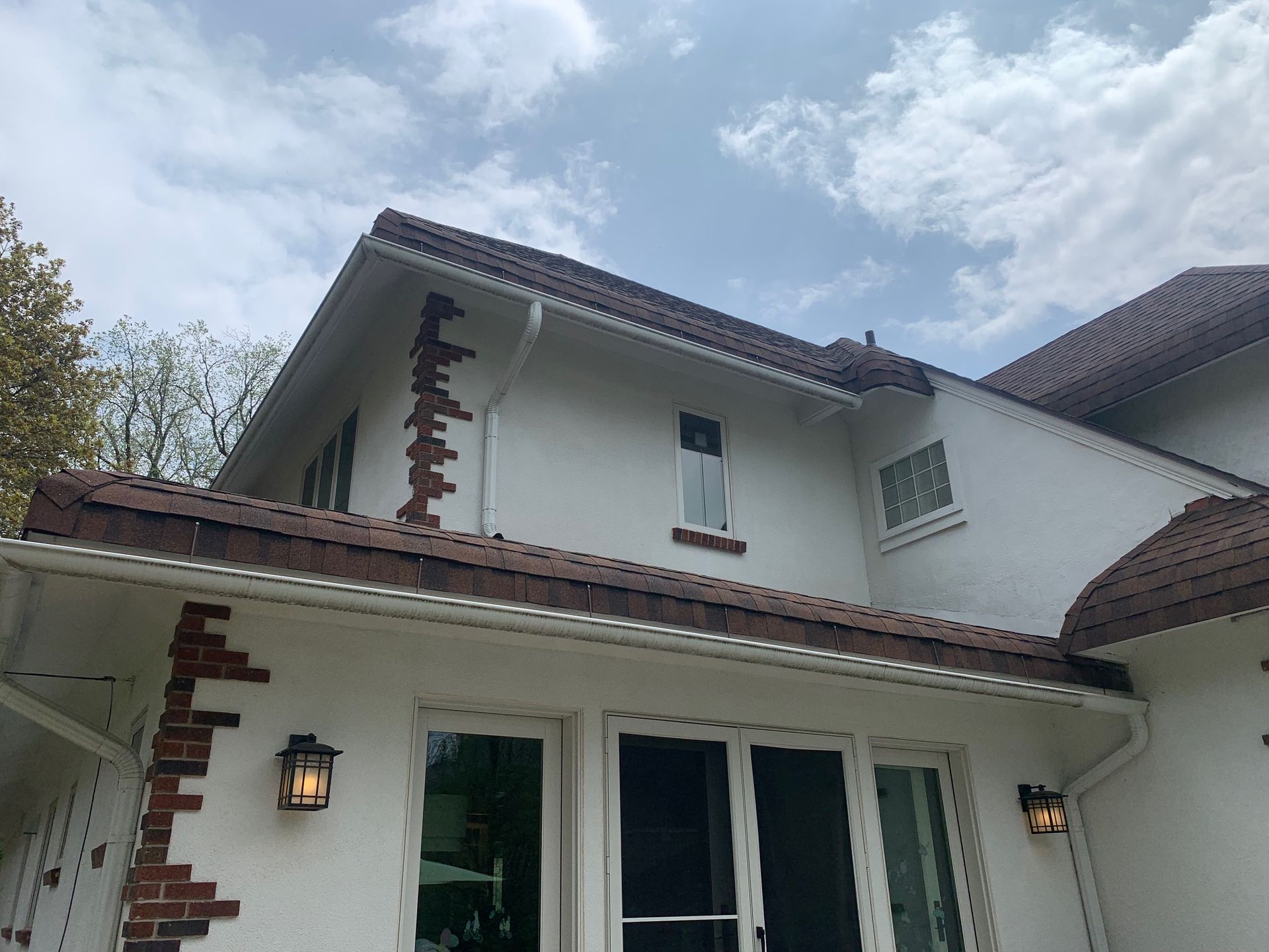 White two-story house with red-tiled roof and lanterns under a cloudy sky