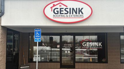 Storefront of GESINK Flooring & Exteriors with glass doors and an accessible parking sign outside.