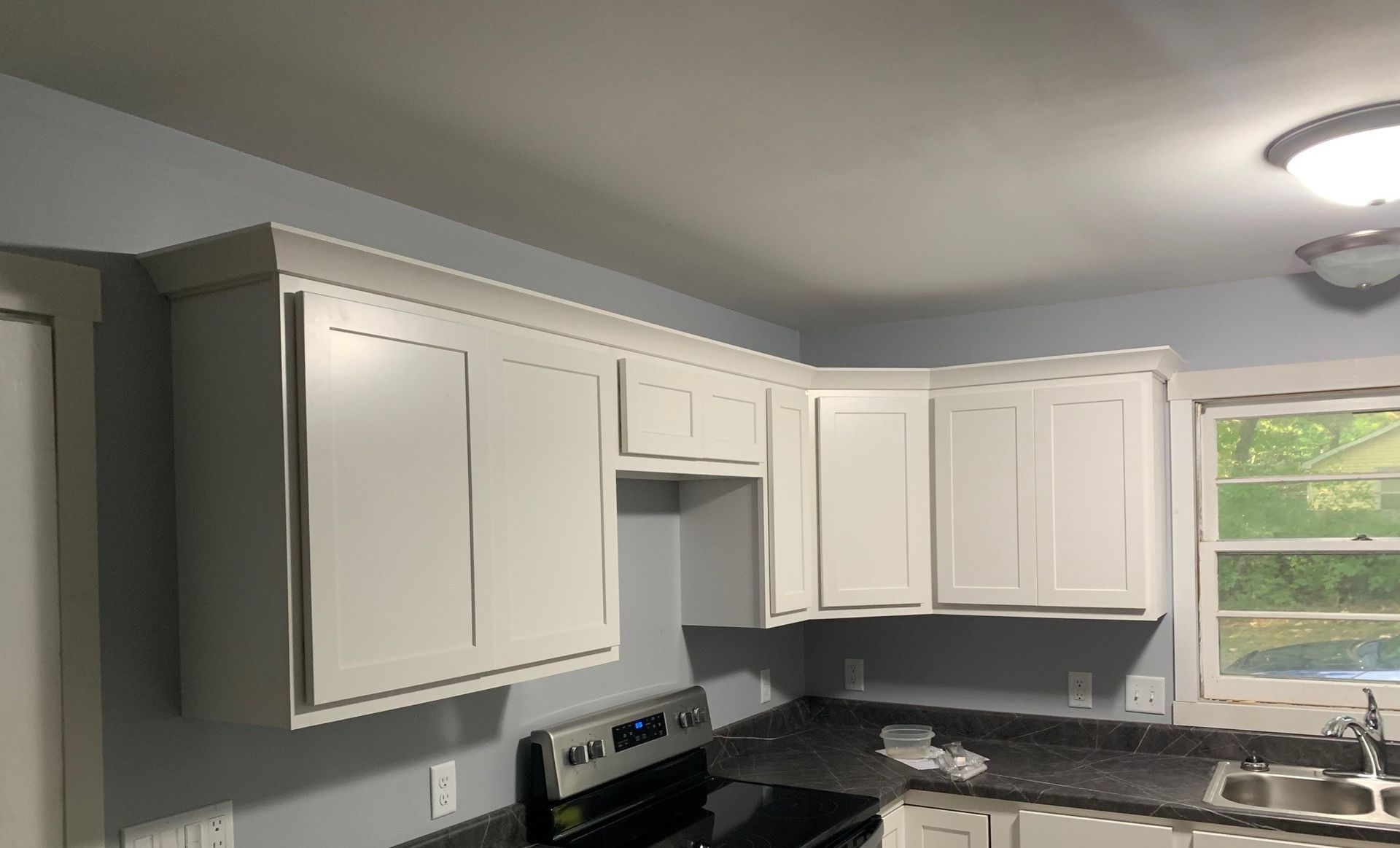 White kitchen cabinets with black countertops and a window over the sink