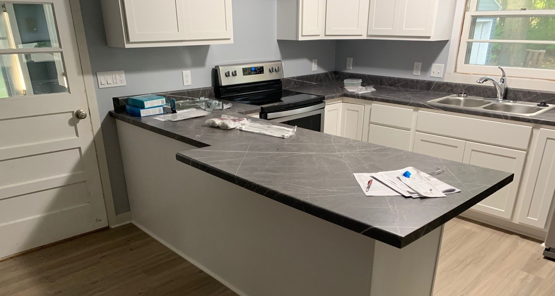 Modern kitchen with white cabinets, gray counters, and a black island countertop.
