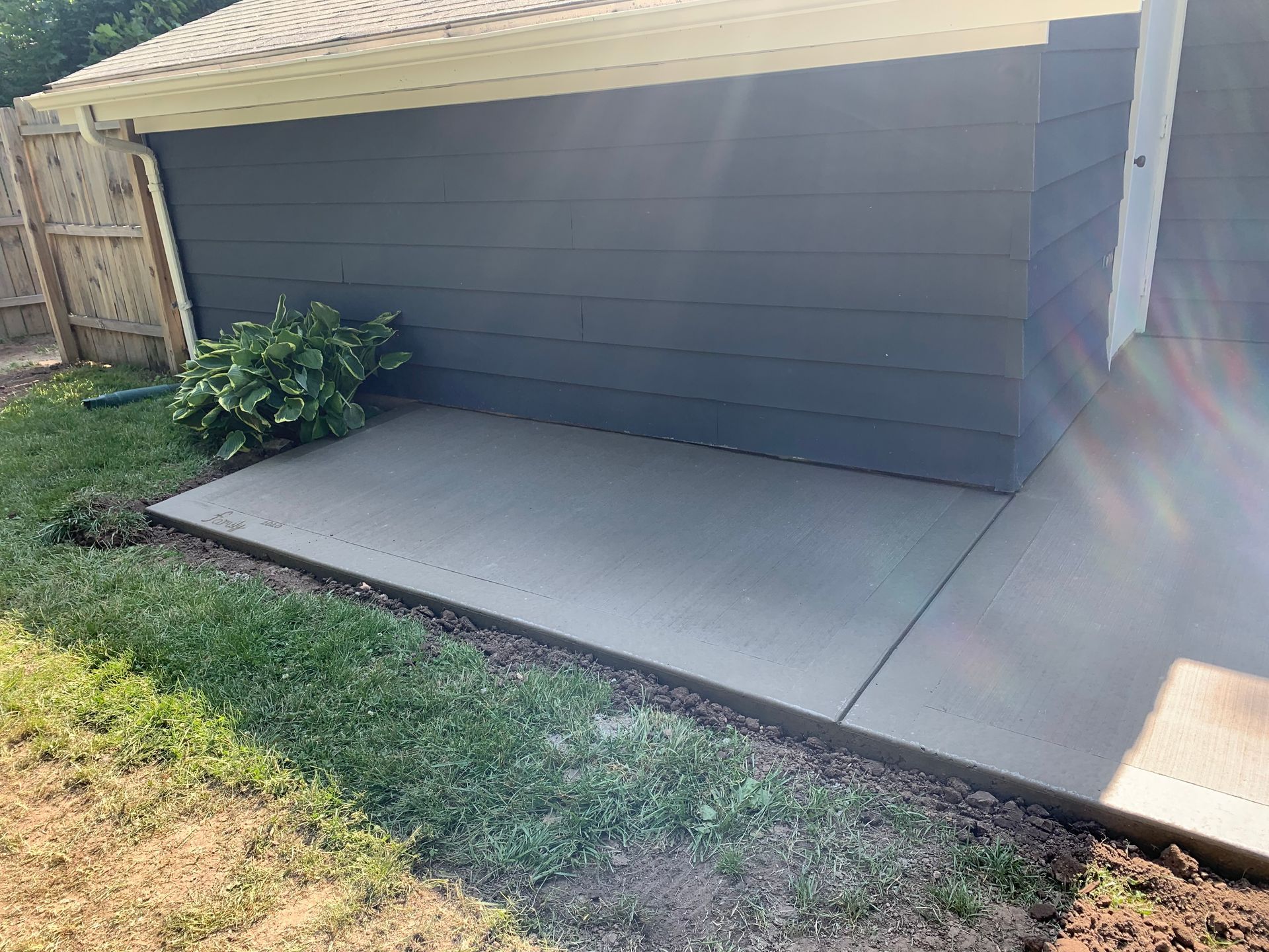 Gray accessibility ramp beside a house with a small plant and grass lawn