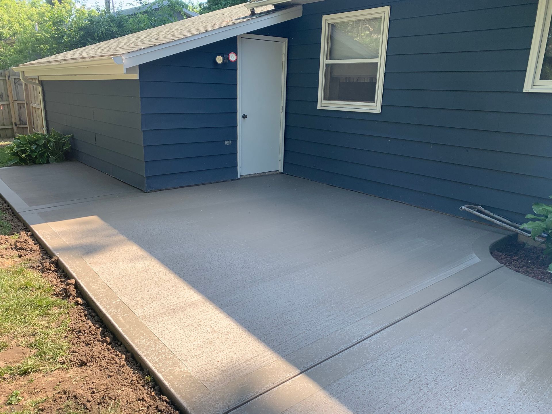 Concrete walkway leading to a white door on a blue house exterior