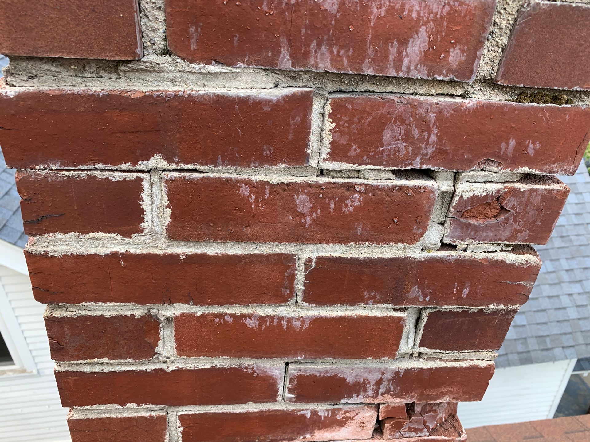 Close-up of a red brick wall with white mortar, showing cracks and worn damage near the edge
