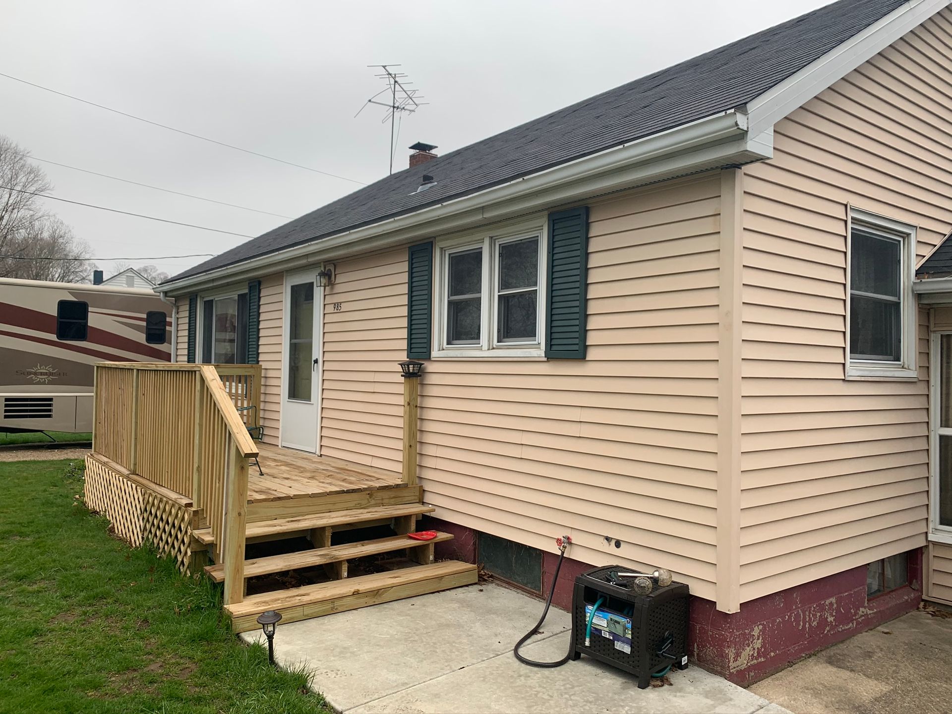 Small beige house with a wooden accessibility ramp and steps on the side.
