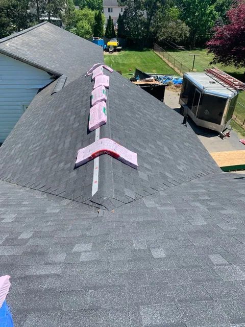 Pink arrows painted on a gray rooftop pointing toward a nearby driveway and house.