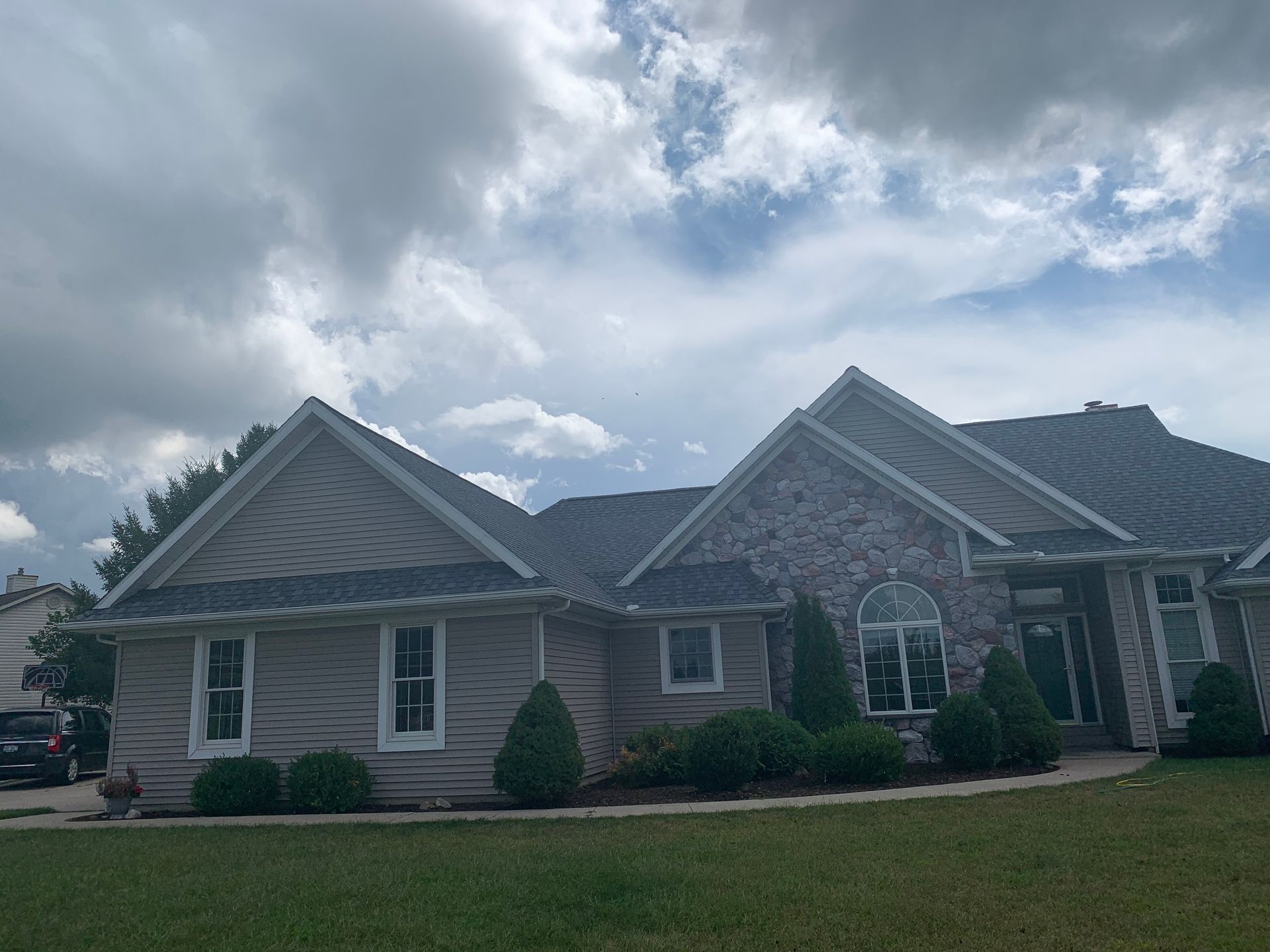 Suburban brick house with gabled roof and cloudy sky